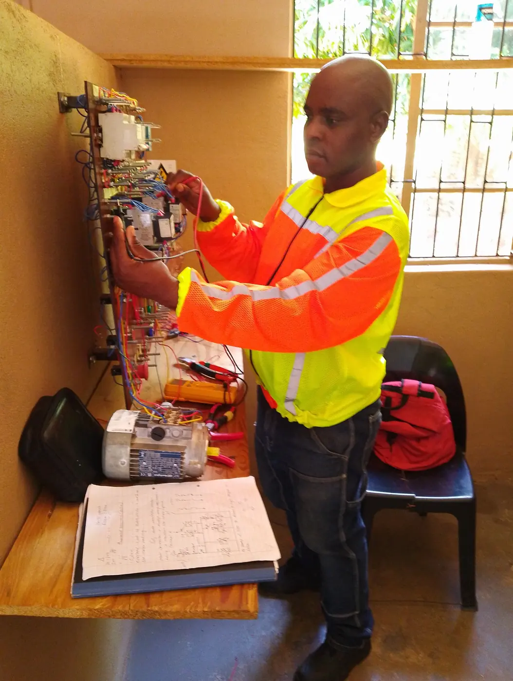 Technician testing an industrial motor control panel