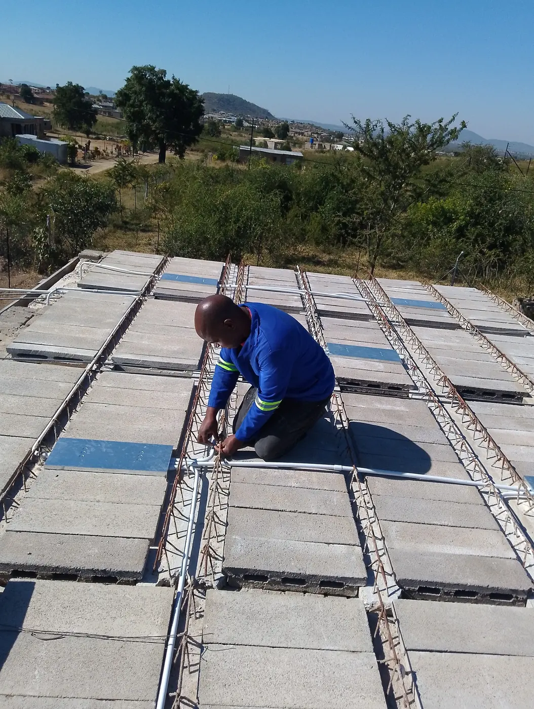 Technician laying electrical conduit across a rib-and-block slab